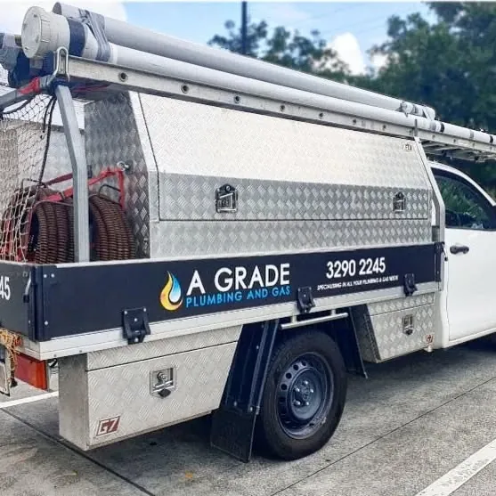 A Grade Plumbing and Gas work ute with an alloy canopy, ladder rack and hose reel, photographed from the side